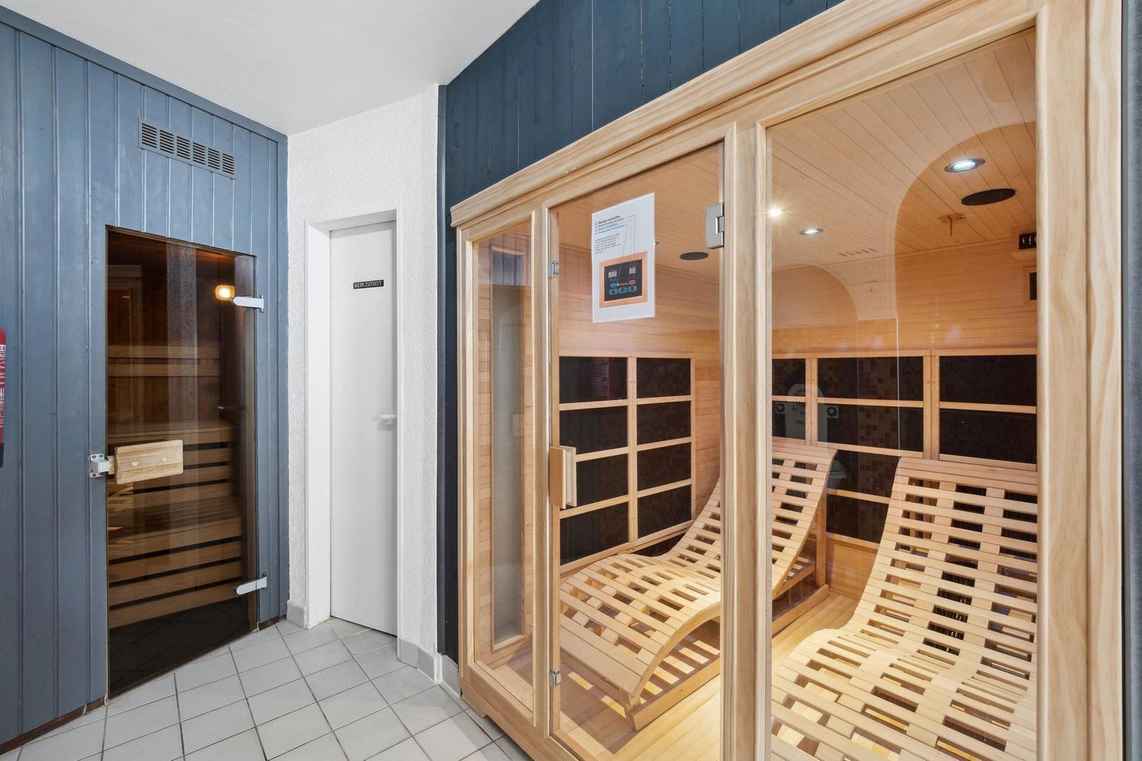 Sauna mit Holzliegen und Glaswand. Nebenher befindet sich eine weitere Sauna.