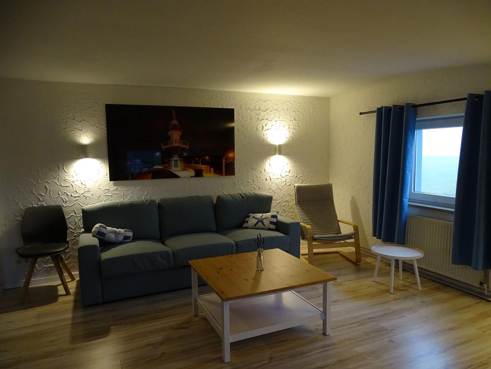 Wohnzimmer mit Sofa, Tisch und Blick aufs Meer.