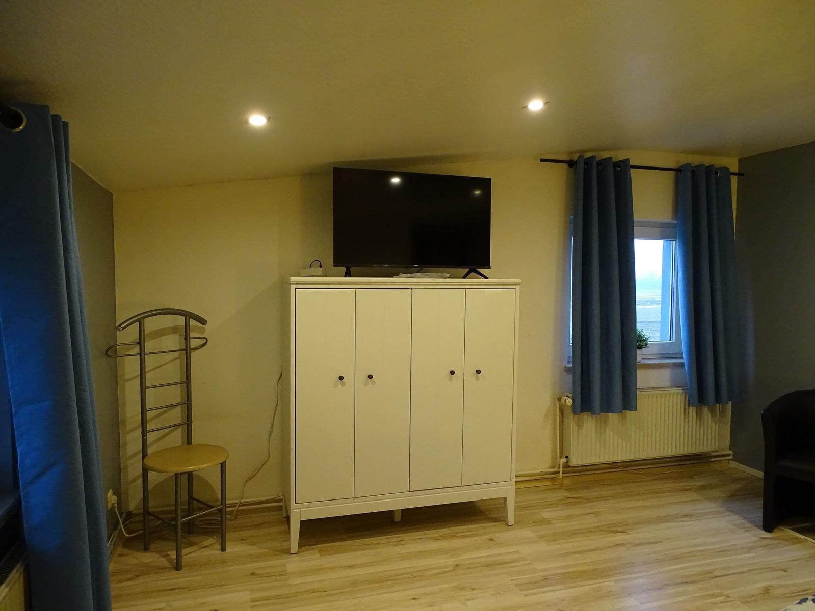 Zimmer mit TV, Kleiderständer und Fenster mit Blick aufs Meer.