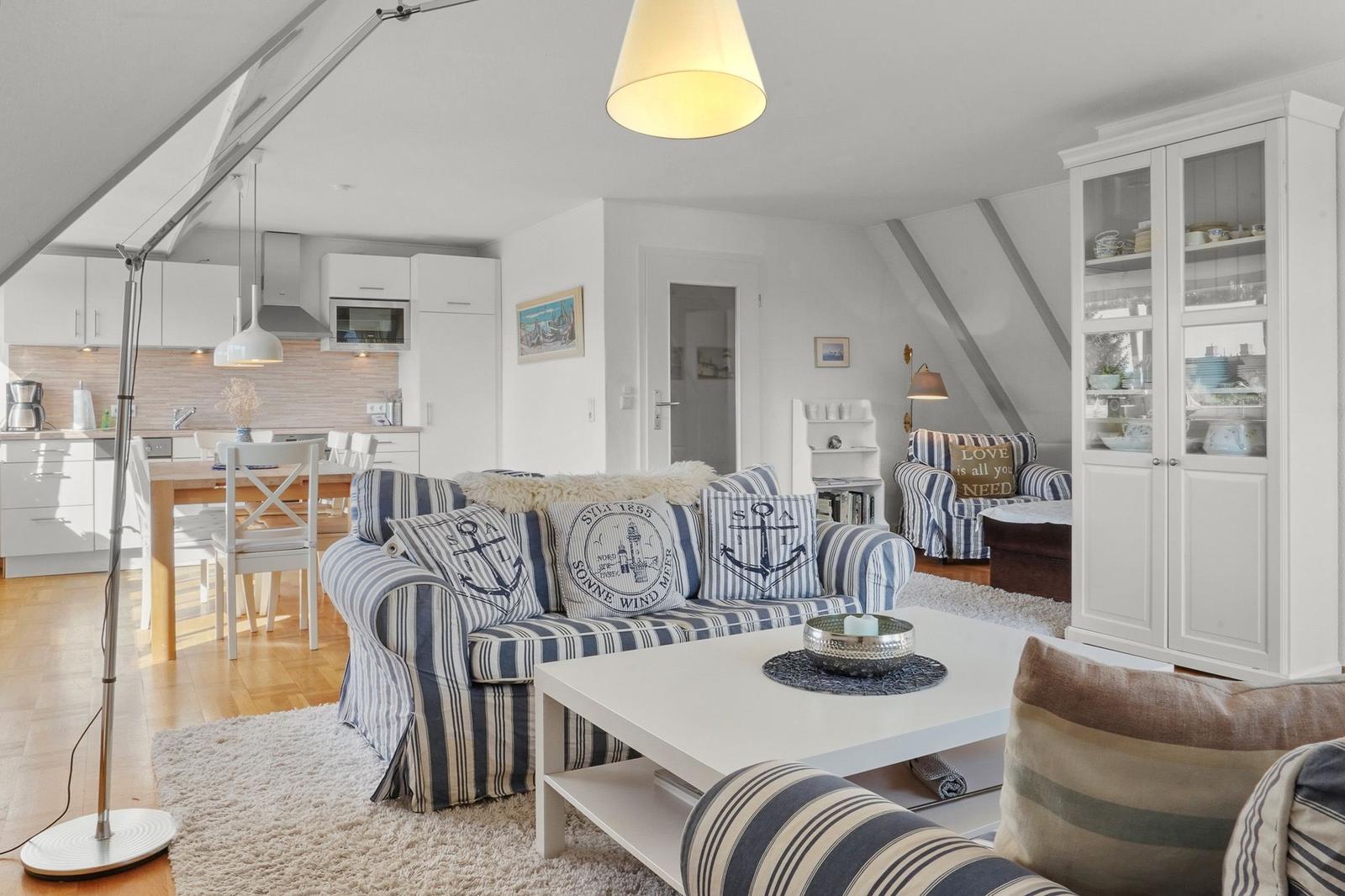 Wohn- und Küchenbereich mit Sofa, Esstisch und Glasvitrine.