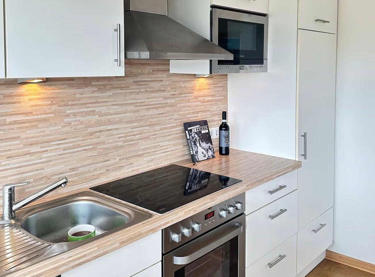 Moderne Küche mit Edelstahlspüle, Herd und Mikrowelle.