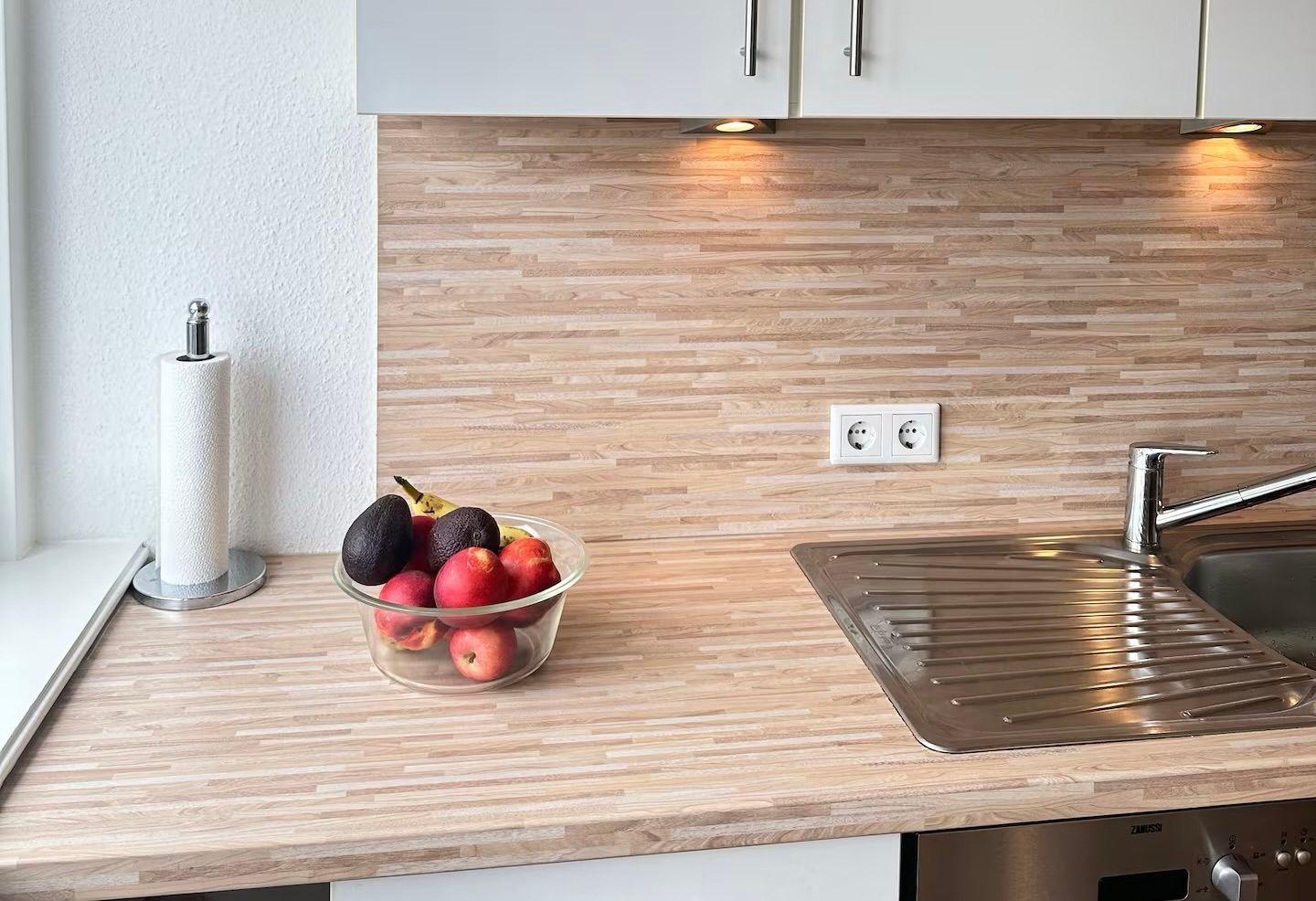 Küche mit Holzrückwand, Spüle und Obstschale