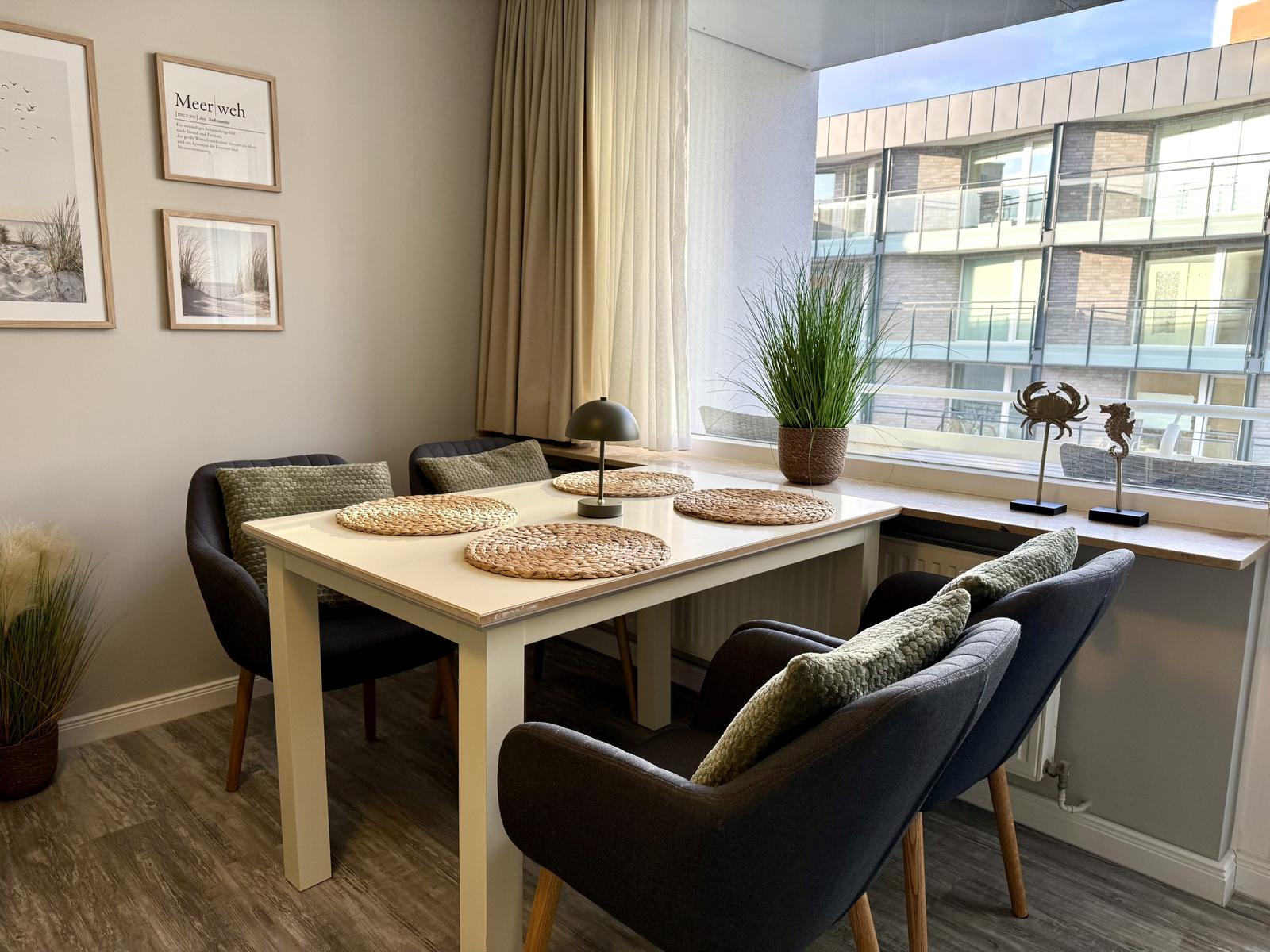 Esstisch mit vier Stühlen und Fensterblick auf Gebäude.