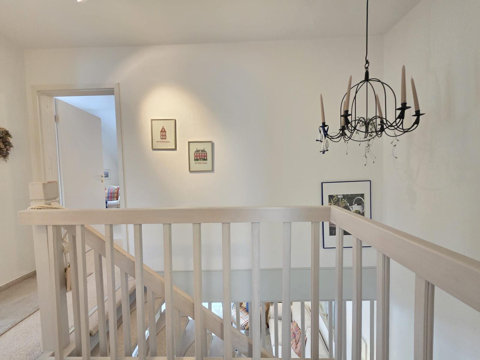 Staircase with white railings and chandelier
