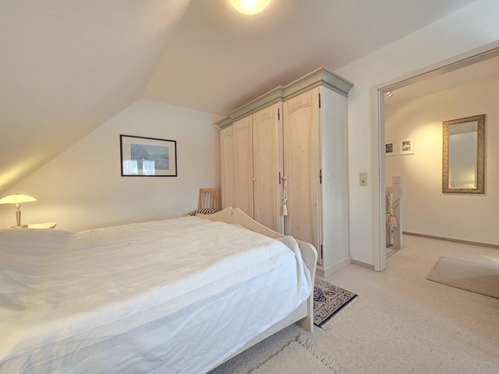 Bedroom with bed, wardrobe, and door to dressing room.