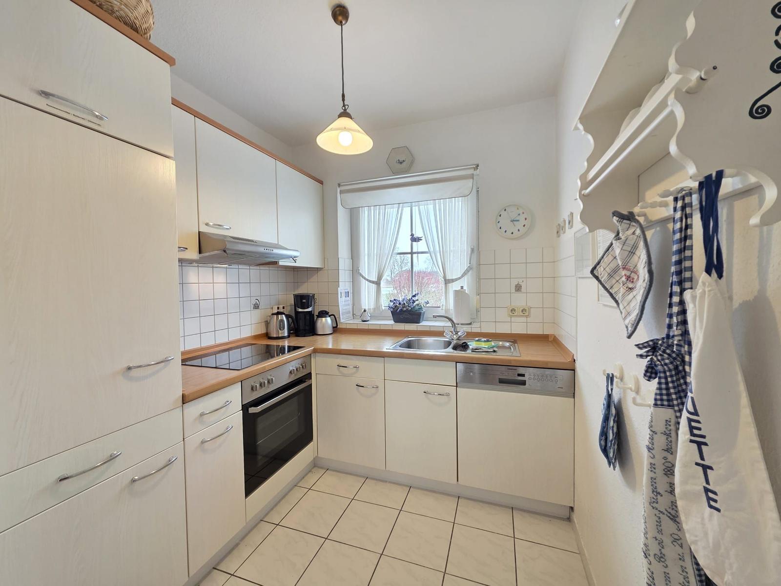Kitchen with white cabinets, wooden countertop, and window with view outside.
