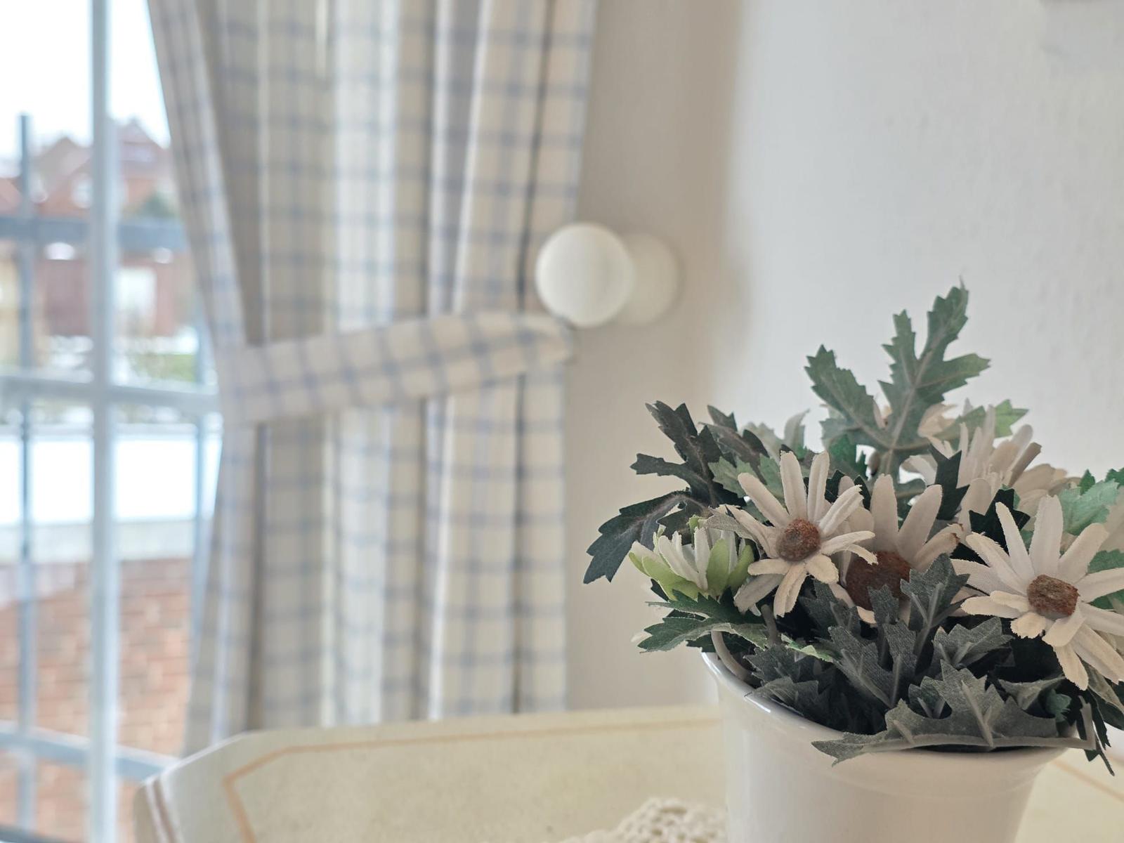 Flower arrangement on table in front of window with checkered curtains