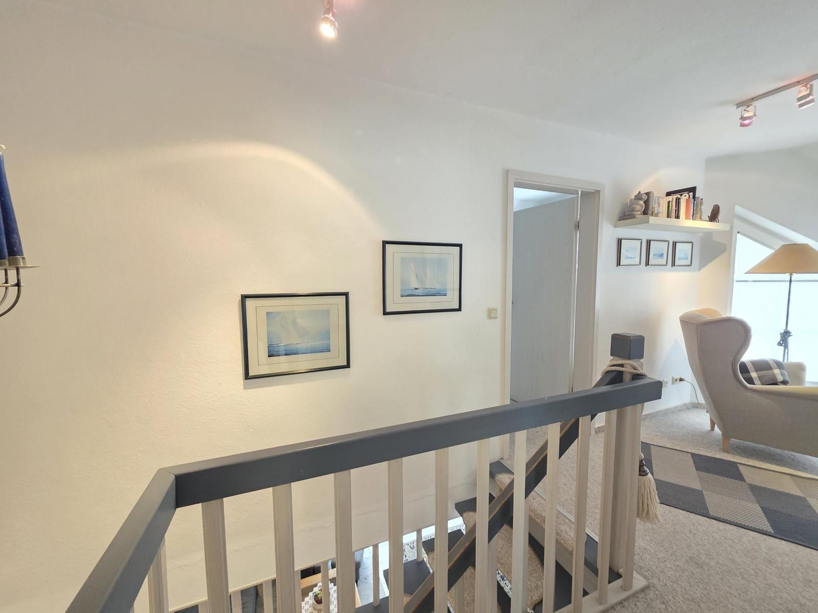 Staircase with pictures on the wall and view into living room.