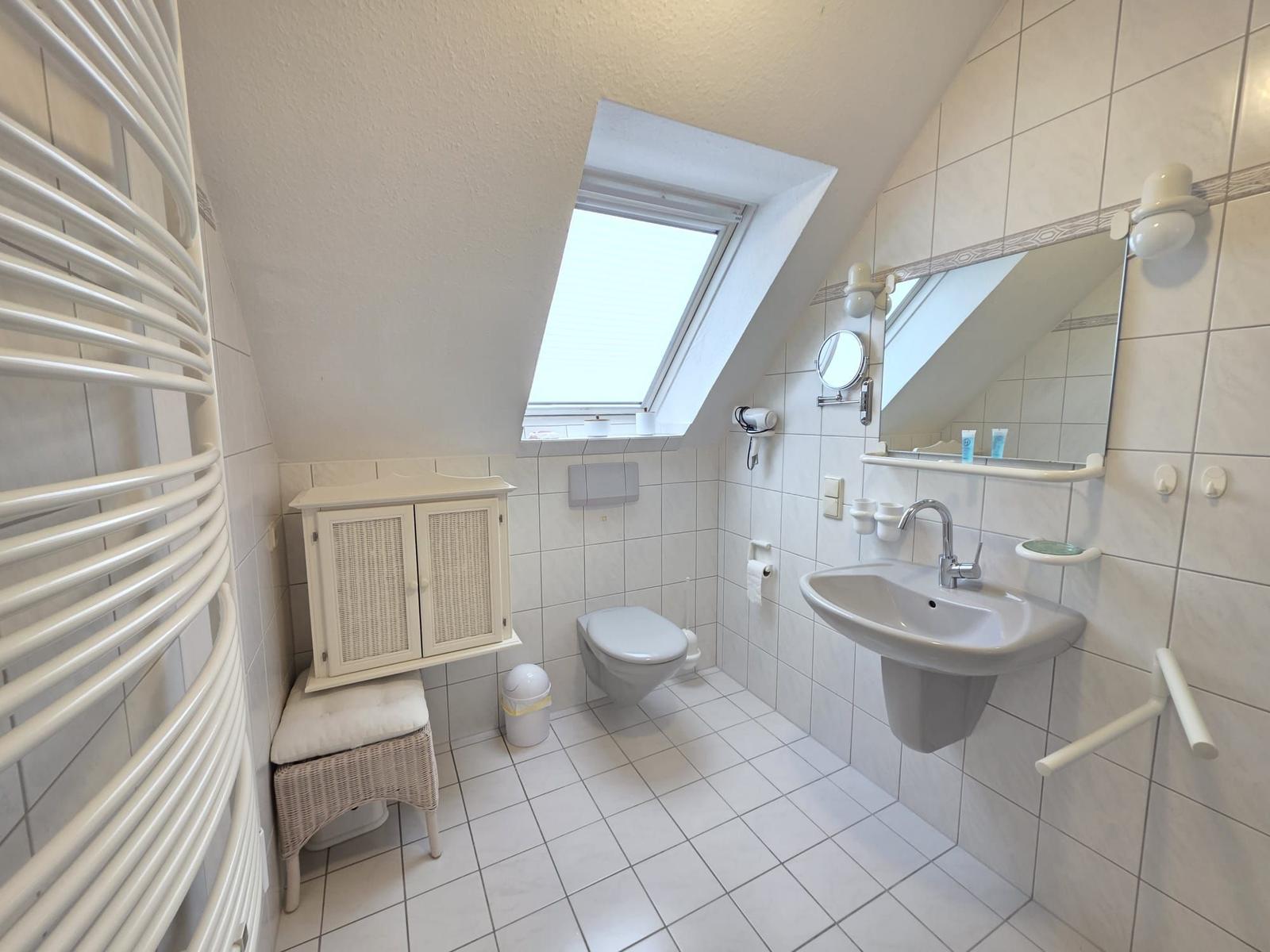 Bathroom with shower, toilet, and sink under sloped ceiling.