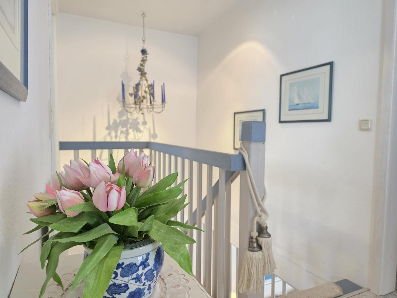 Staircase with flowers, railing, and wall pictures.