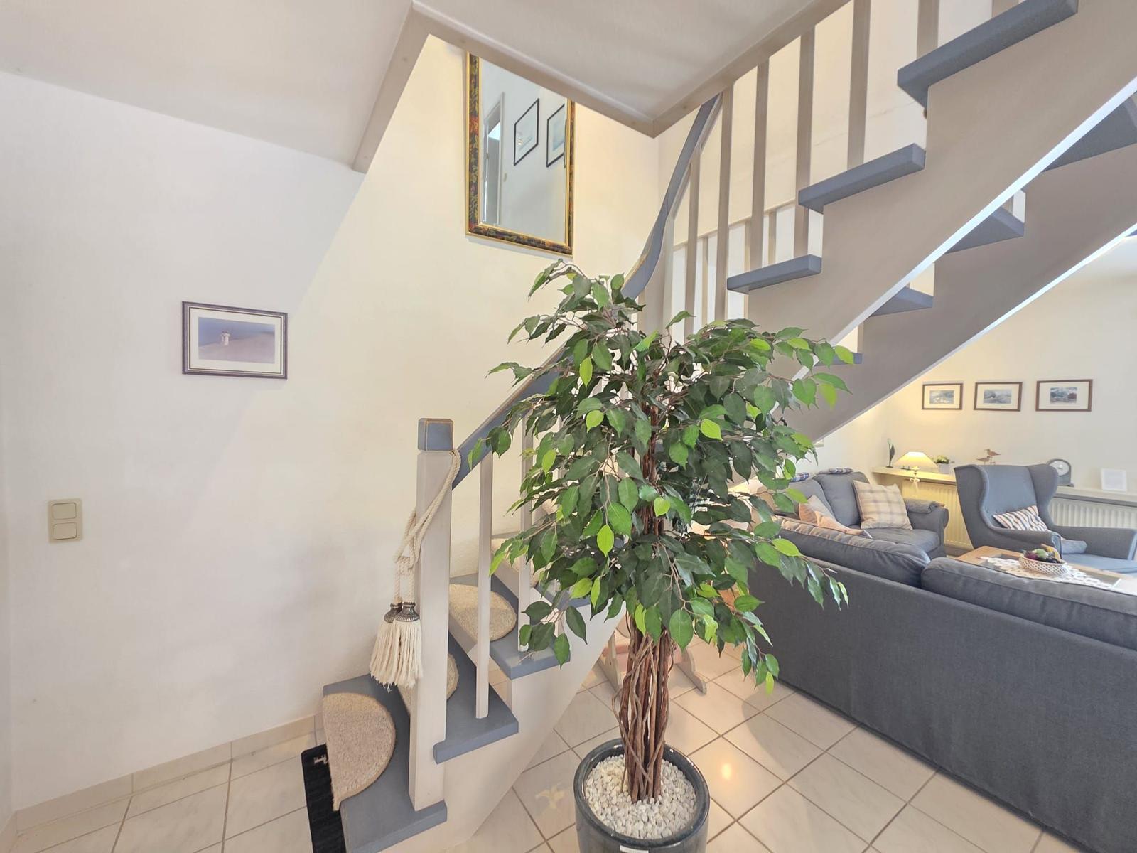 Staircase leads to living room with sofa and plant.