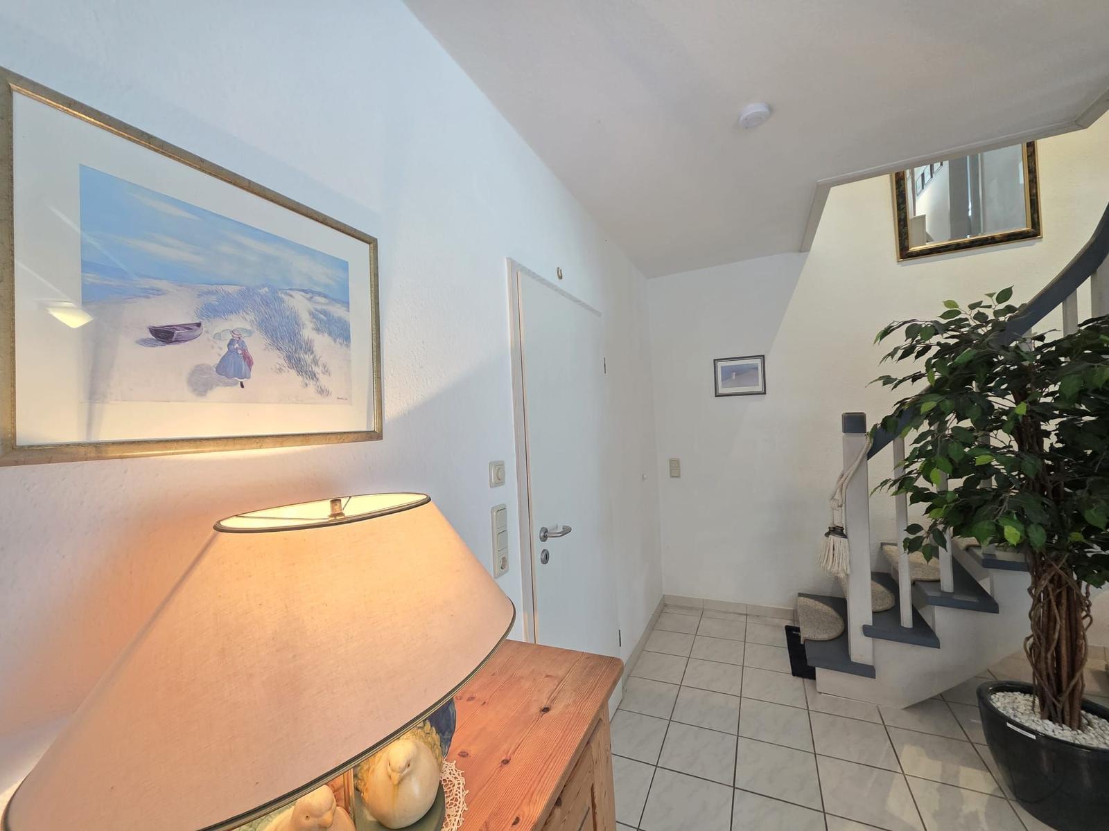 Entrance area with staircase, plant, and lamp on wooden console