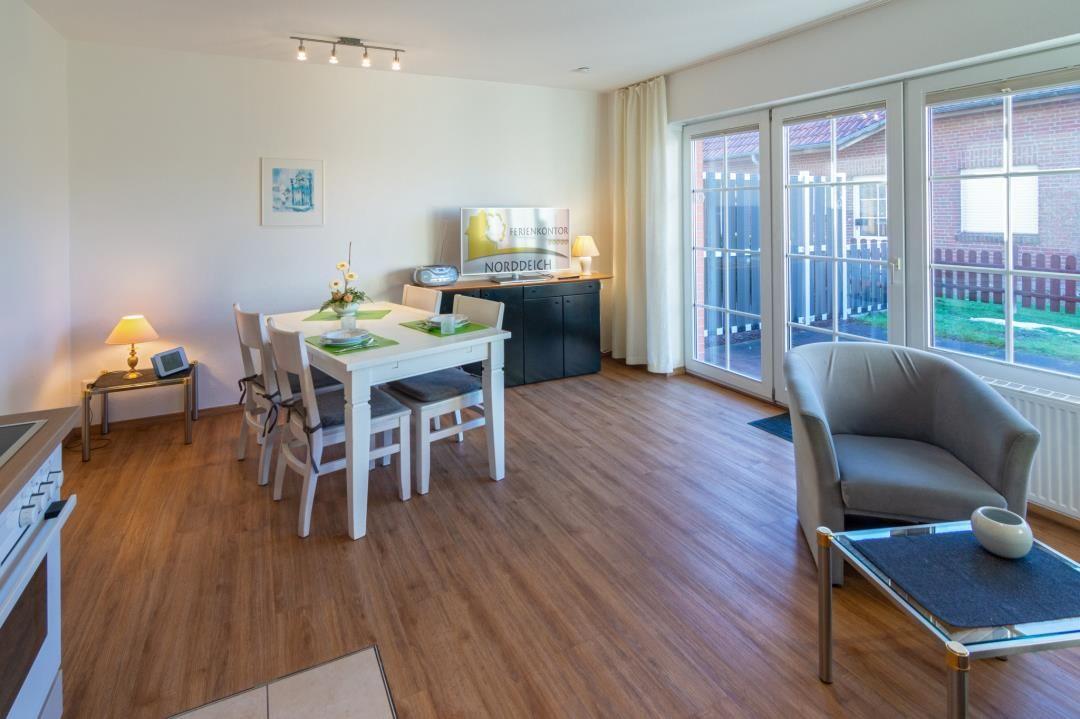 Wohn- und Essbereich mit Tisch, Stühlen, Sofa und Glasfront zur Terrasse.