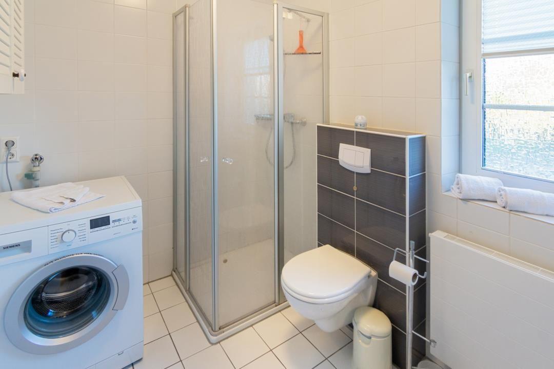 Badezimmer mit Dusche, Toilette und Waschmaschine