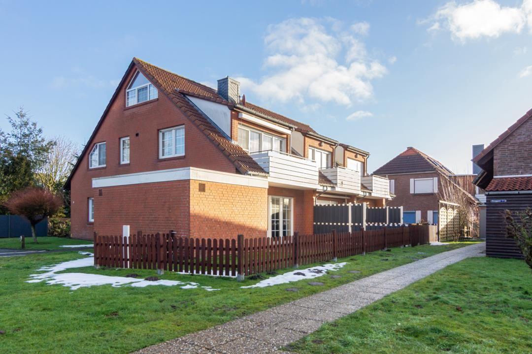 Rotes Backsteinhaus mit Balkon und eingezäuntem Grundstück.