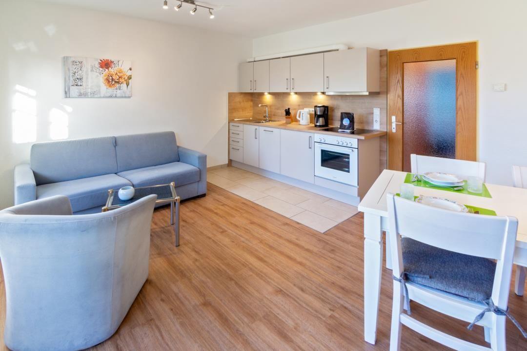 Wohnküche mit Sofa, Esstisch und moderner Küchenzeile.