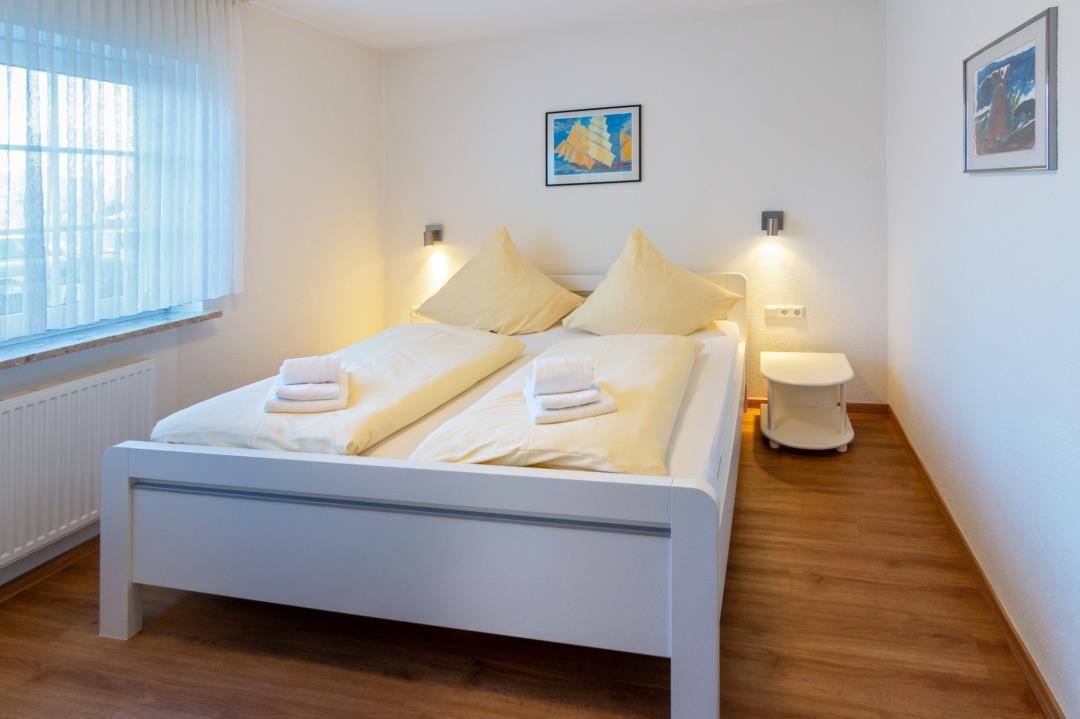 Schlafzimmer mit Doppelbett, Fenster und Wandlampen.