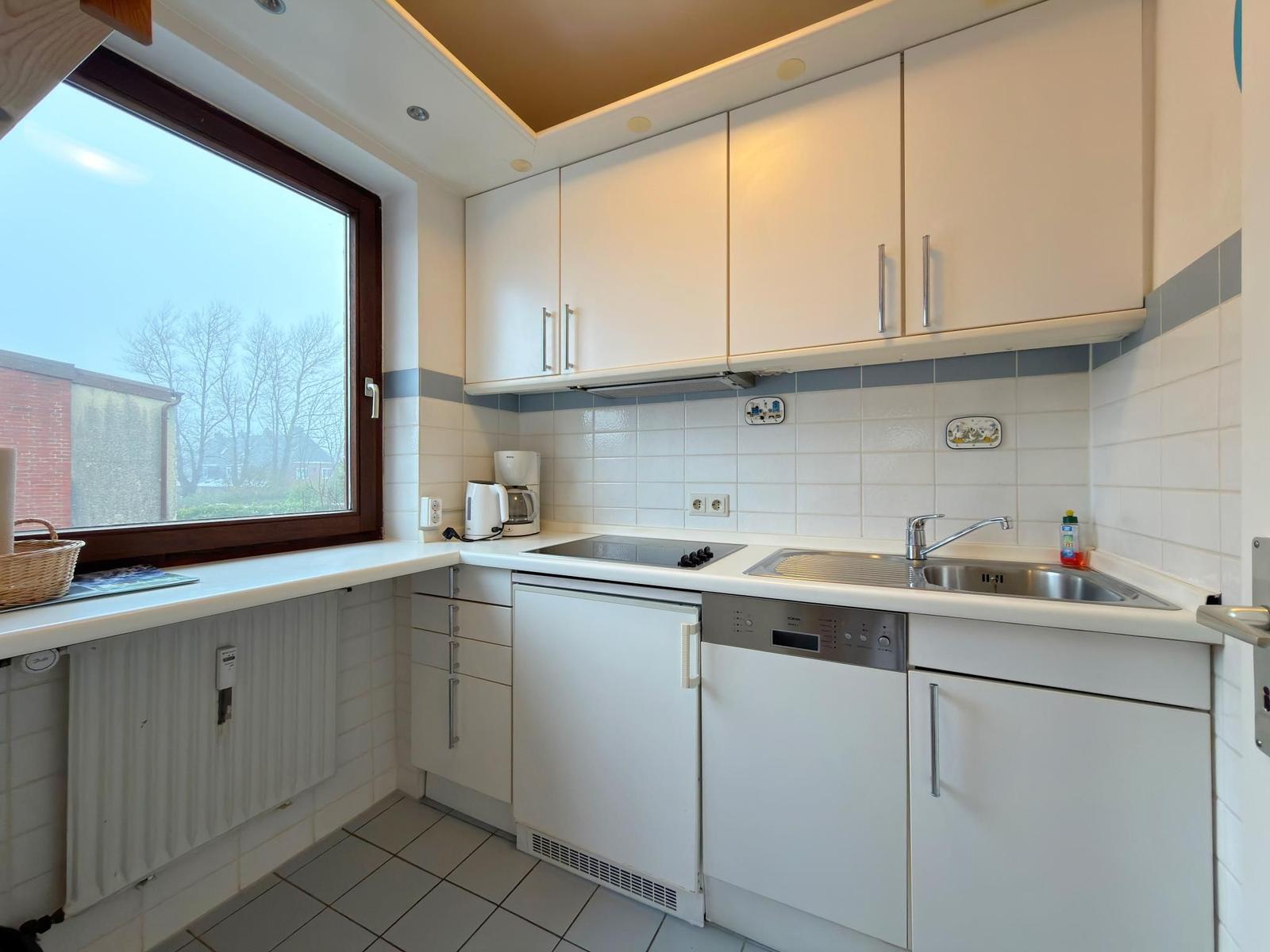 Küche mit Fenster, Spüle, Herd und Waschmaschine.