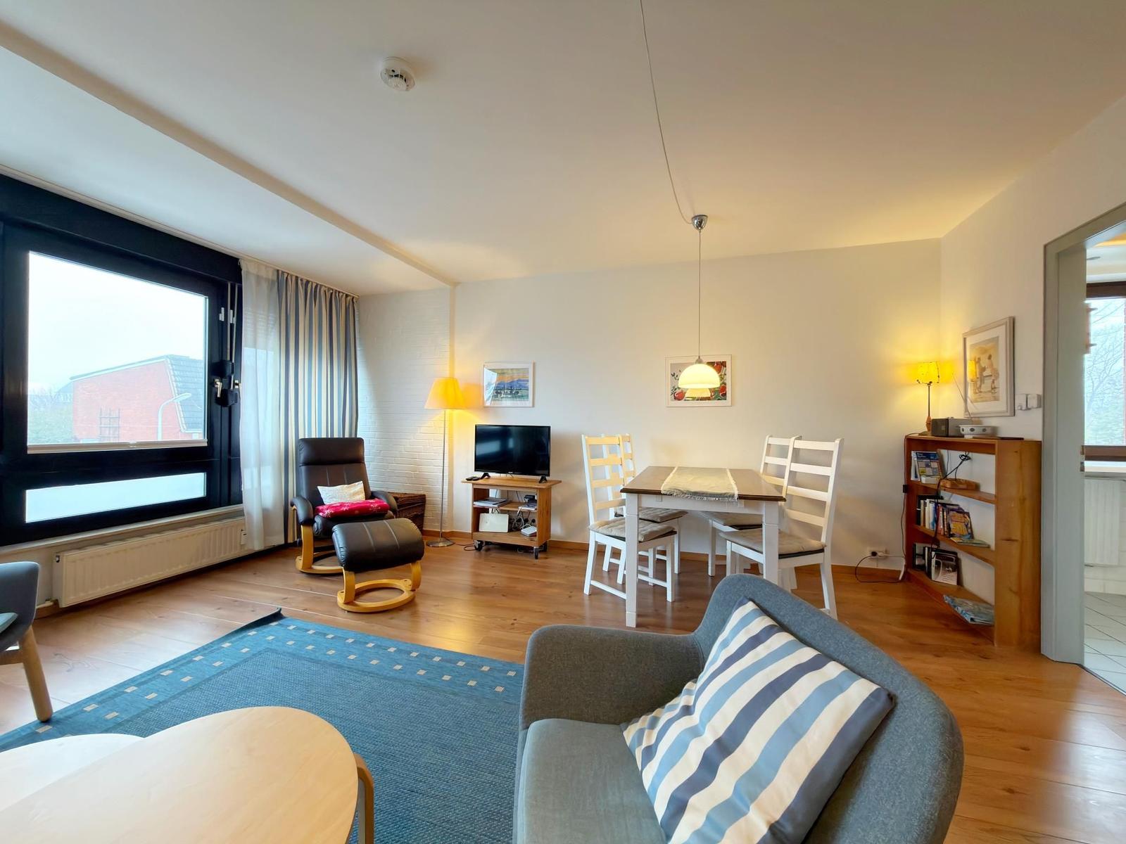 Wohn- und Essbereich mit Sofa, Esstisch und Fernseher.