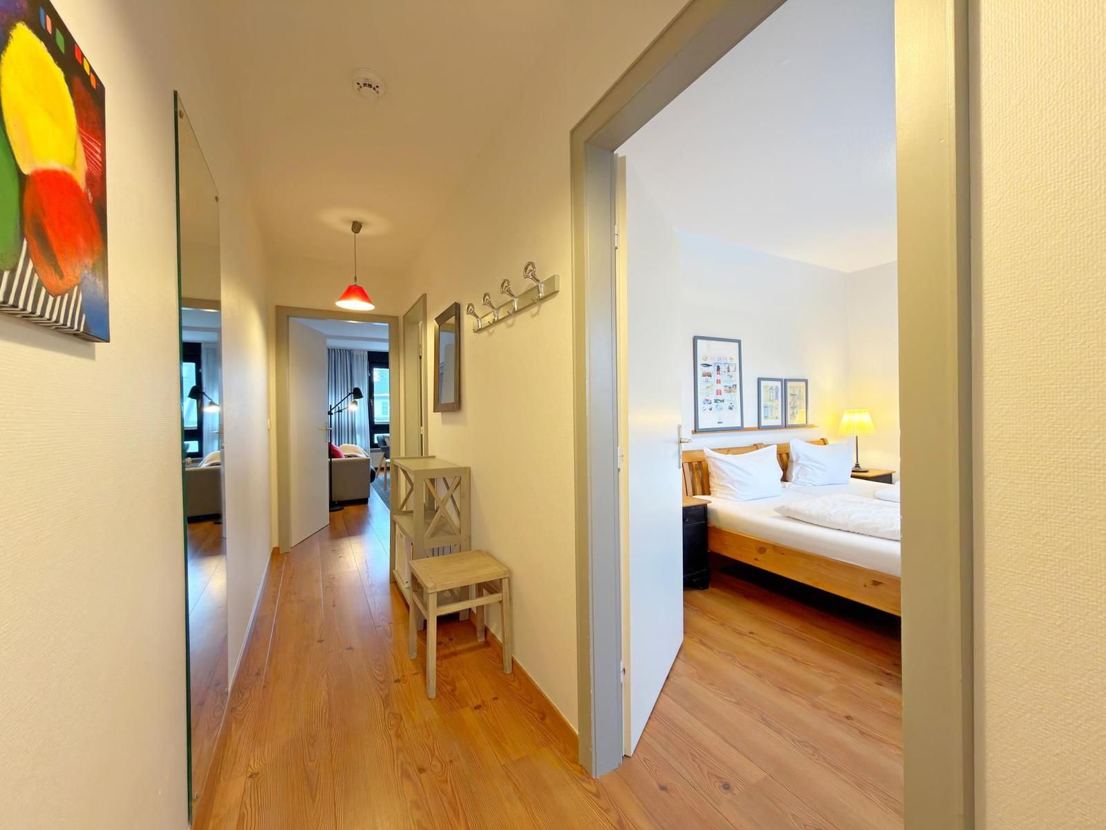 Flur mit Schlafzimmer und Wohnbereich. Holzfußboden und Wanddekoration.