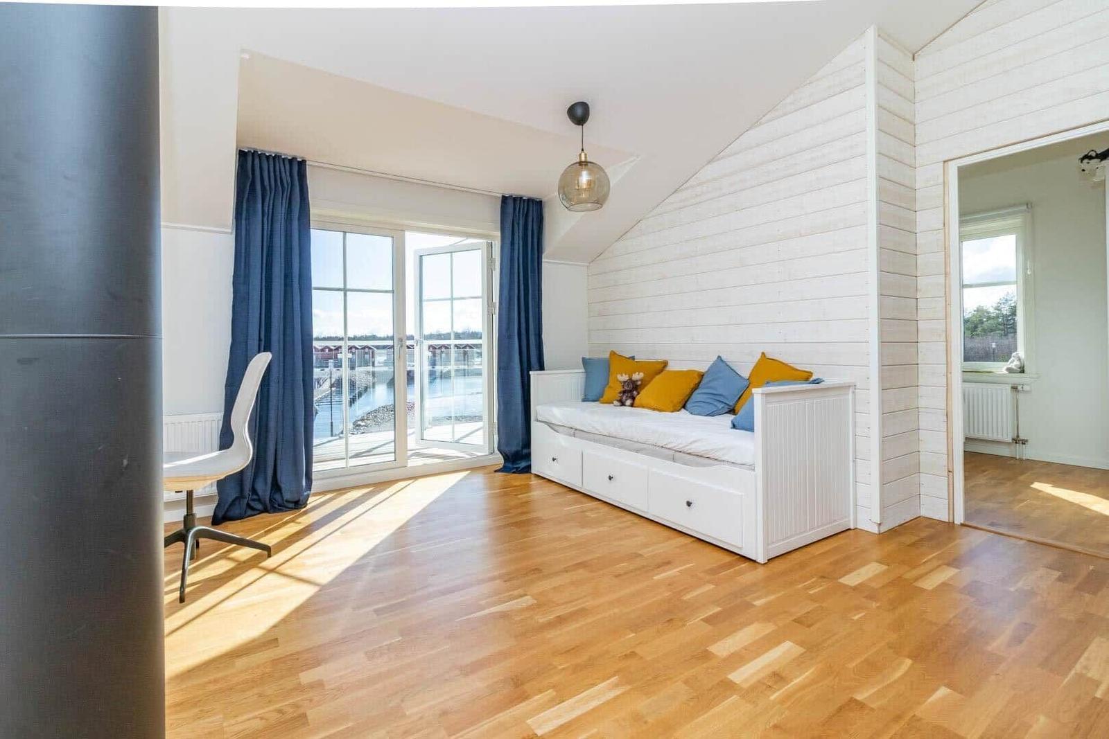Zimmer mit Bett, Holzboden und Blick auf Wasser