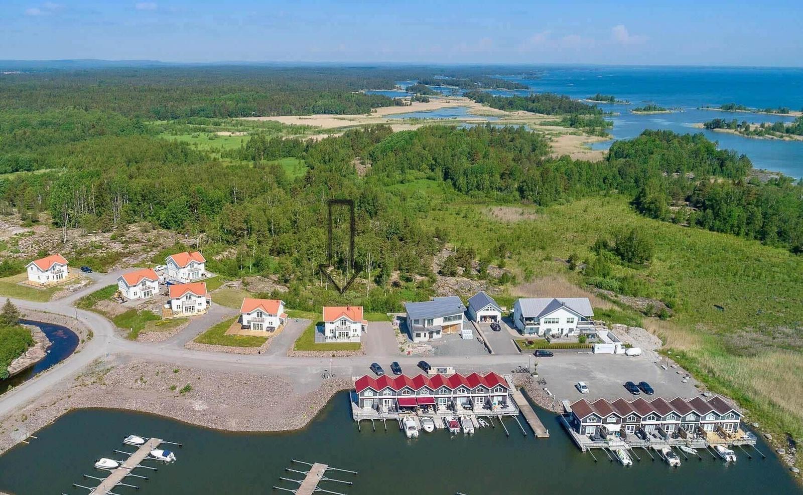 Häuser am Wasser mit Bootsanlegern und Wald im Hintergrund.