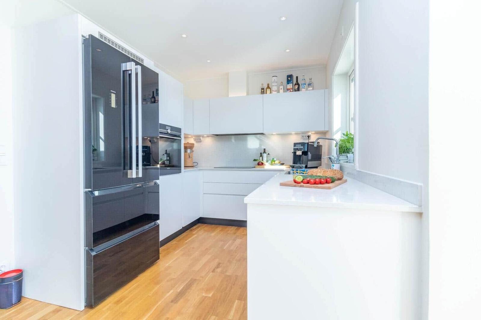 Moderne Küche mit Edelstahlkühlschrank und Arbeitsplatte mit frischen Zutaten.