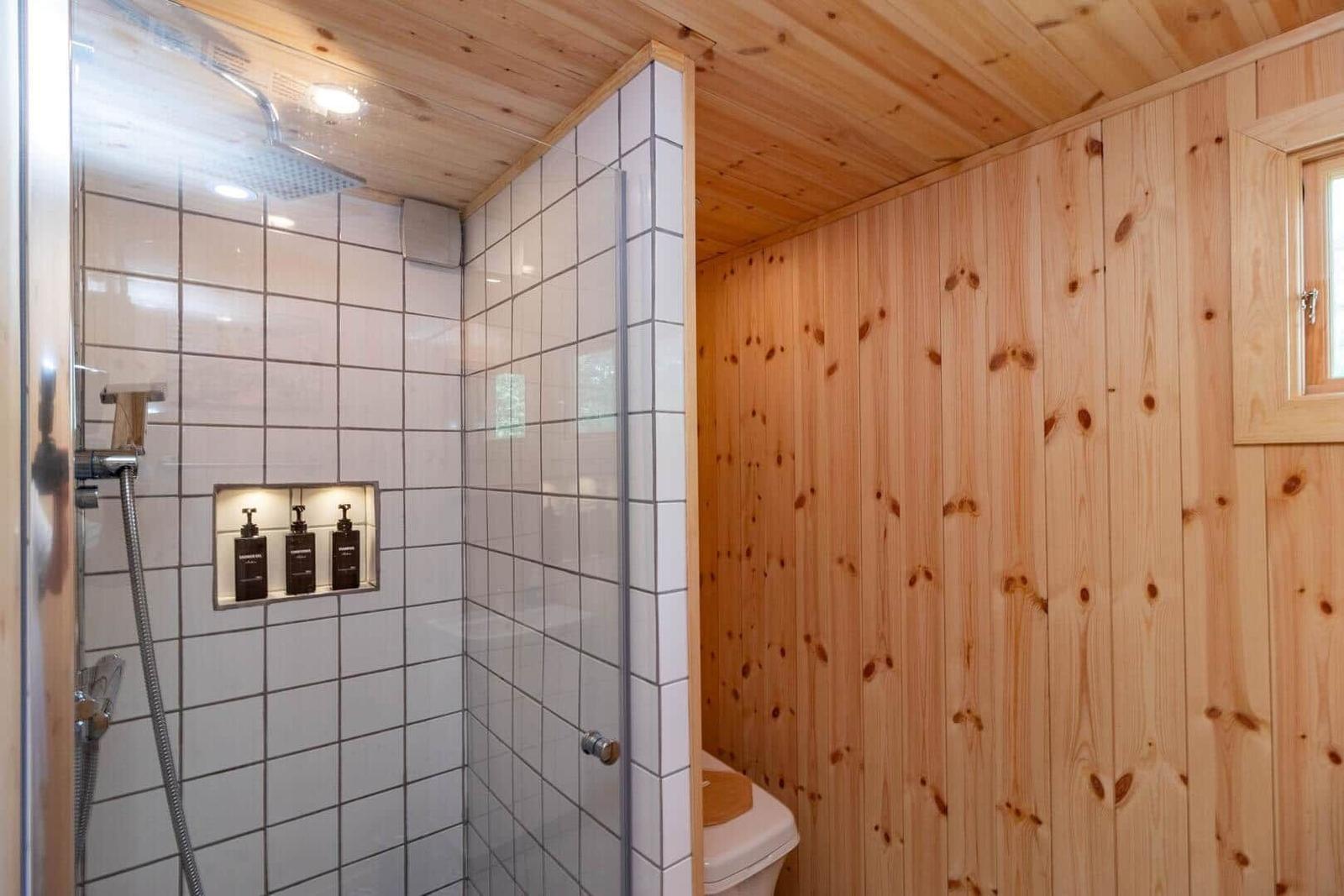 Bad mit Dusche, Toilette und Holzwandverkleidung