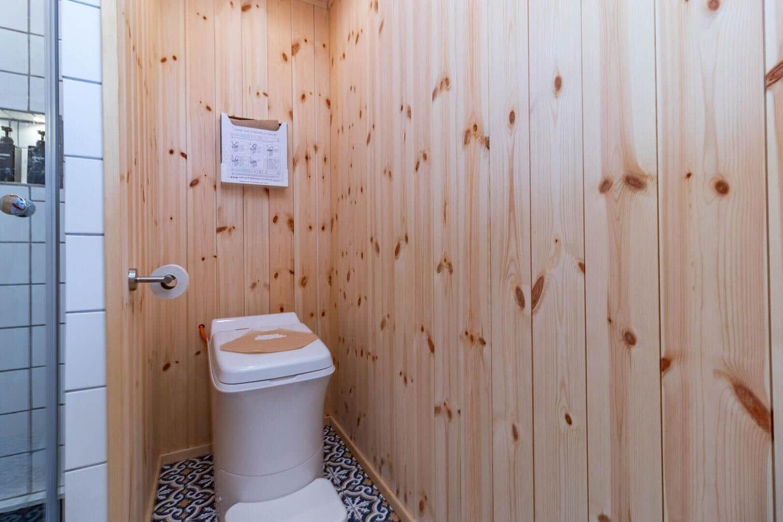 Bad mit Holzwänden, Toilette und Dusche.