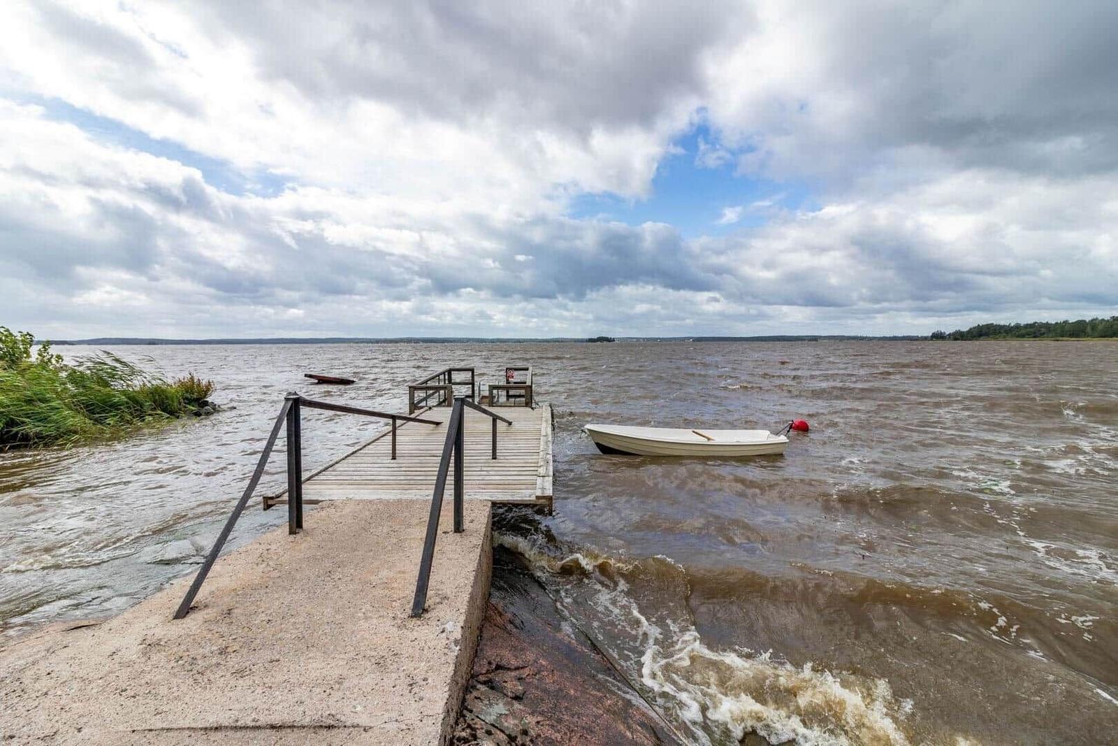 Holzsteg mit Bootssteg und kleinem Boot am Ufer.