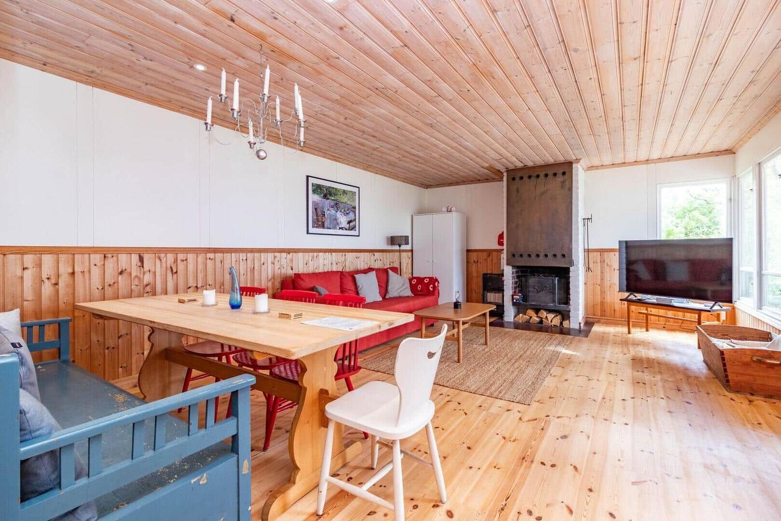 Wohn- und Essbereich mit Holzdecke, Kamin und TV. Holzfußboden und rustikale Möbel.