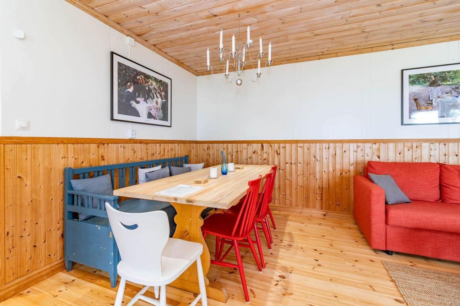 Essbereich mit Holztisch, roten Stühlen und blauer Bank. Wohnbereich mit rotem Sofa.