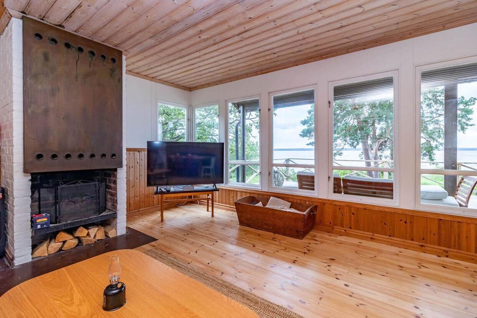 Wohnzimmer mit Kamin, Fernseher und Blick auf Wasser.