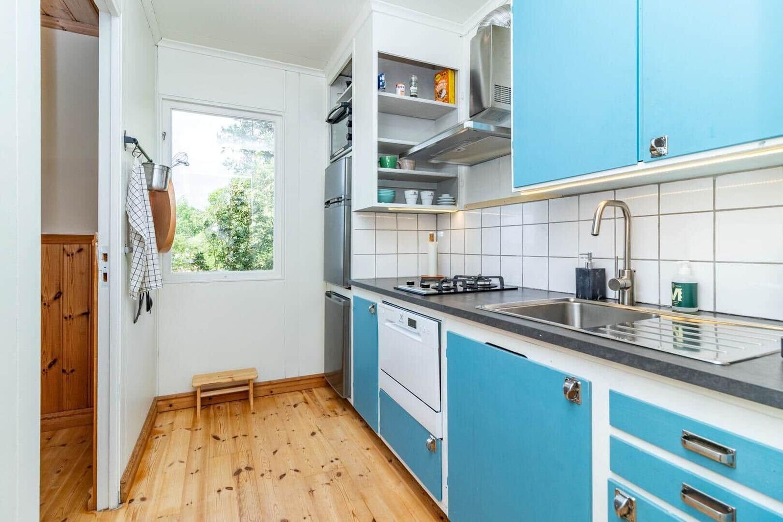 Küche mit blauen Schränken, Edelstahlgeräten und Holzboden.
