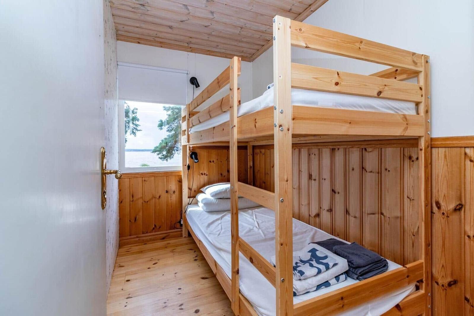 Zimmer mit Holzbett, Fenster und Blick auf Wasser
