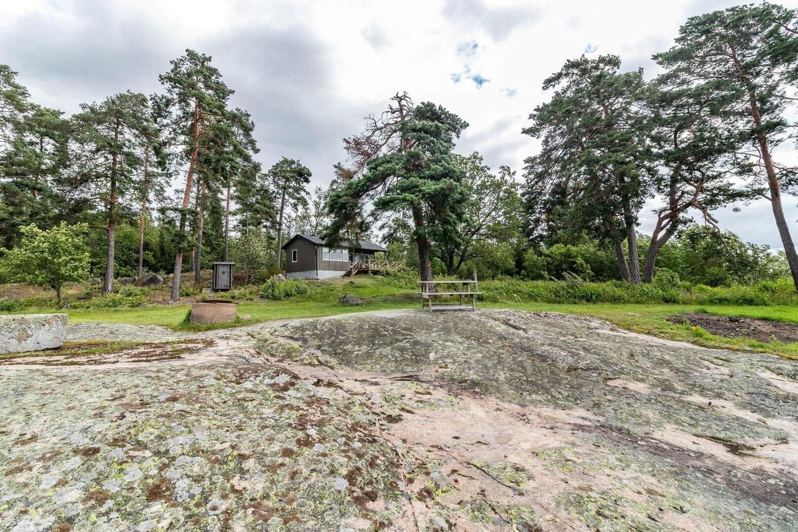 Haus mit Terrasse in Wald, umgeben von Felsen und Bäumen.