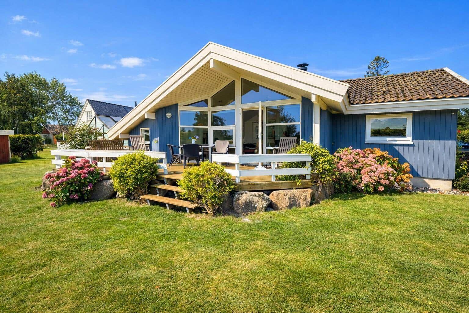 Blue house with terrace and garden. Visible: wooden steps, flowers, and garden furniture.