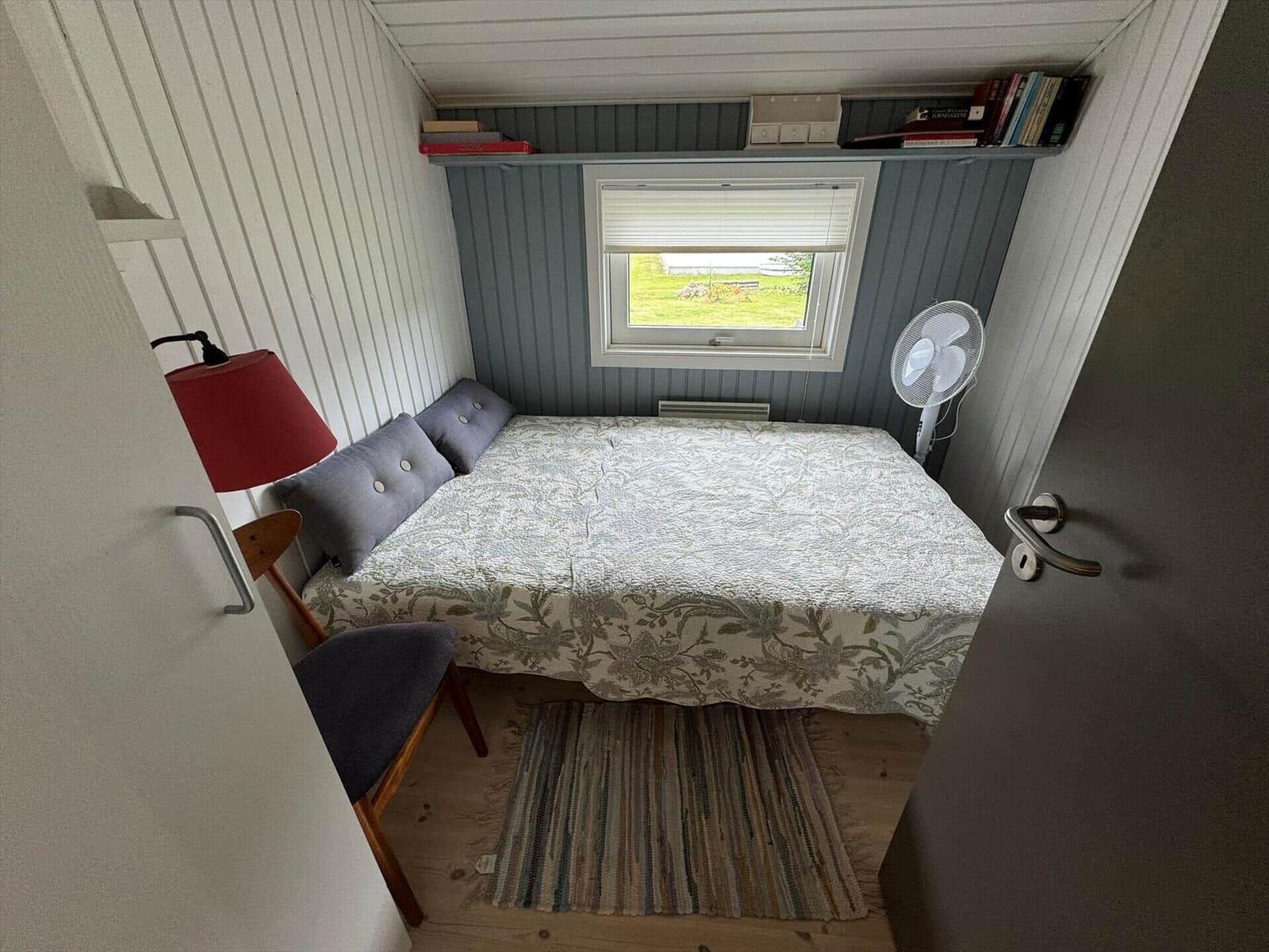 Bedroom with bed, window, chair, and fan.