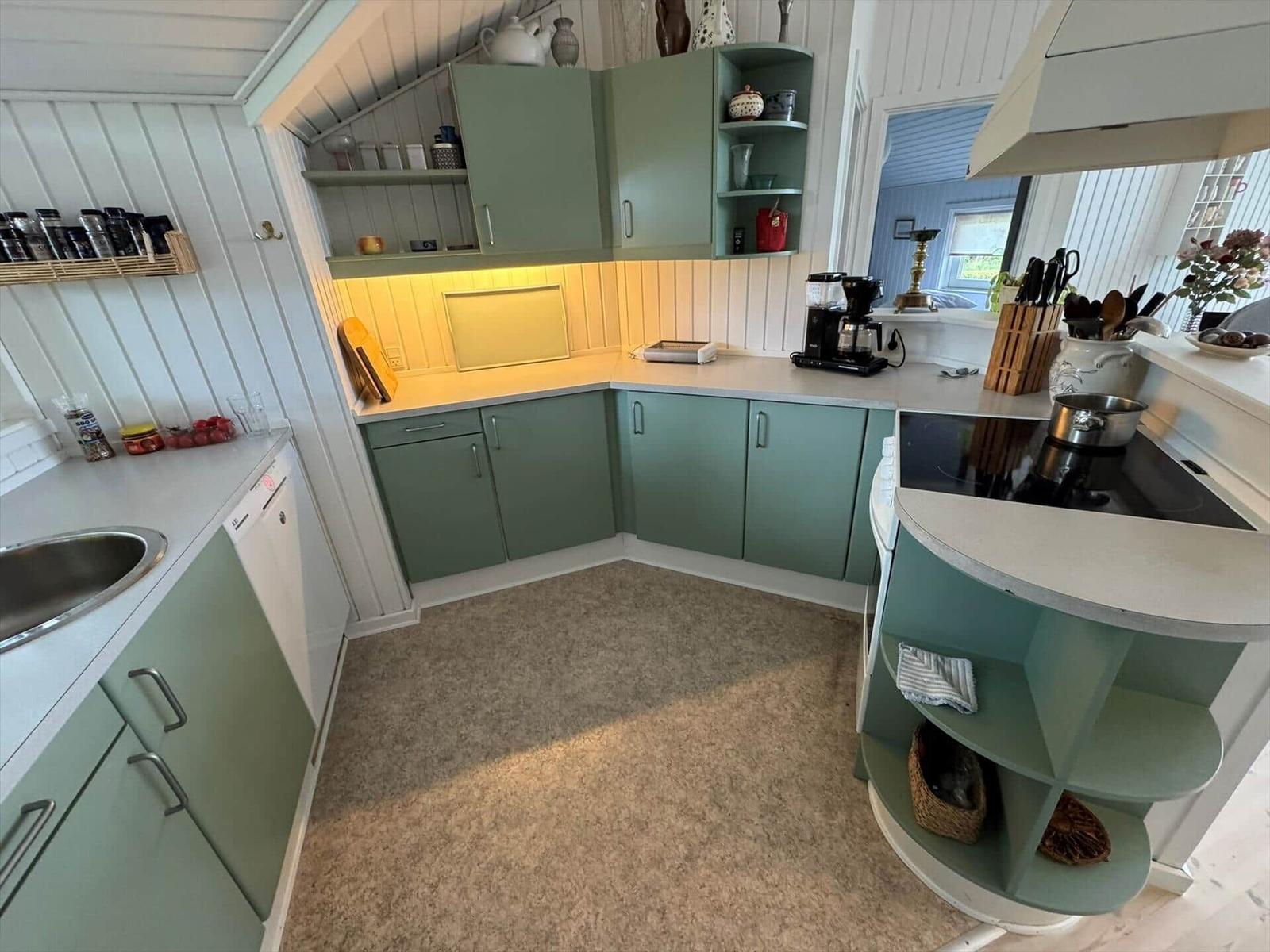 Kitchen with green cabinets, countertop, and stovetop.