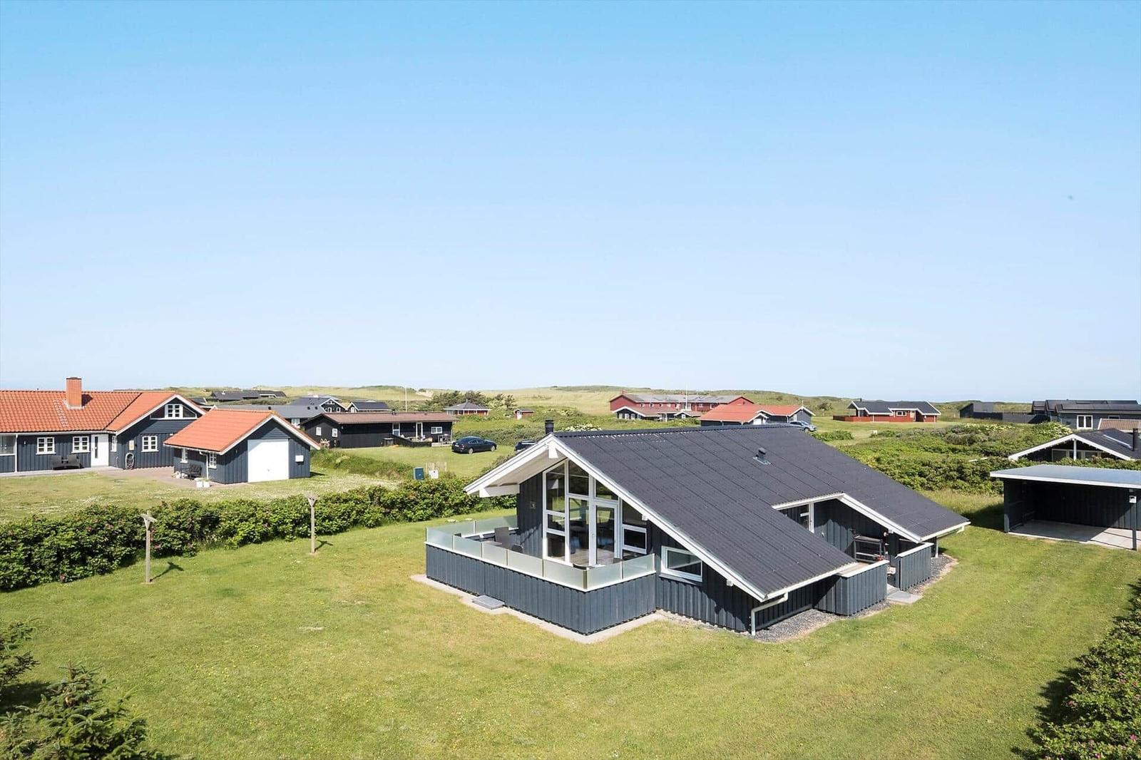 Moderne Villa mit großem Garten und Terrasse. Umgeben von traditionellen Häusern und Grünflächen.
