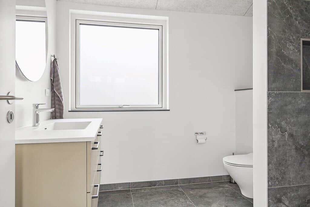 Badezimmer mit Waschbecken, Toilette und Fenster