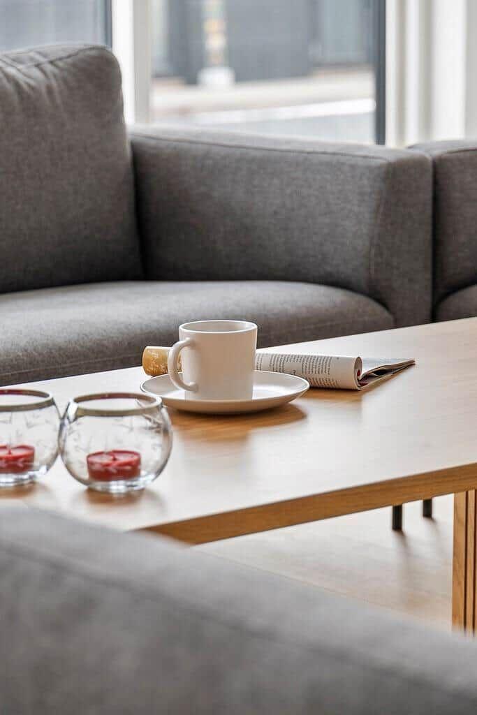 Ein grauer Sofa mit Tisch, Tasse, Zeitschrift und Kerzenhaltern.