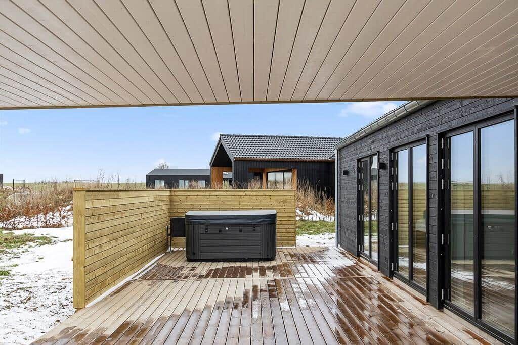 Terrasse mit Whirlpool und Holzverkleidung. Sicht auf moderne Häuser im Hintergrund.