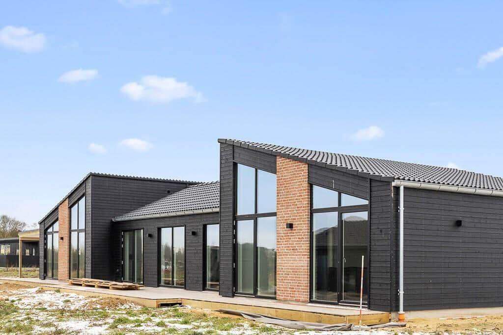Moderne Villa mit großen Fenstern und schwarzem Holzverkleidung.