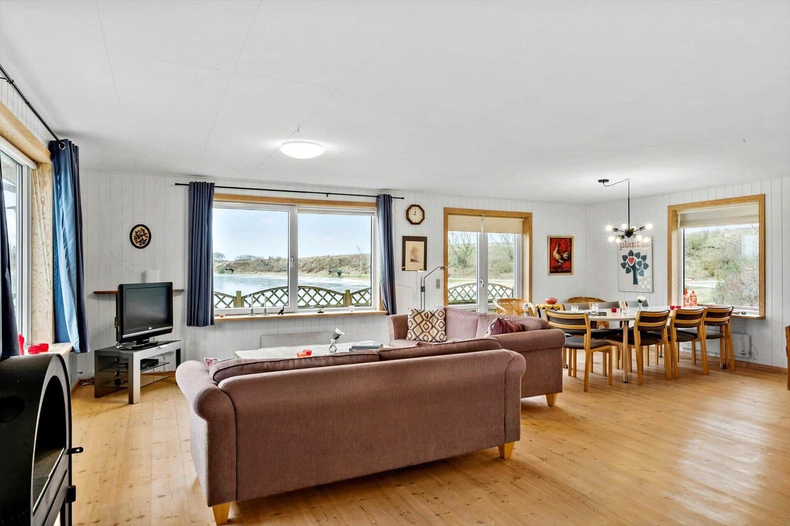 Living and dining area with sofa, TV, and view of water.