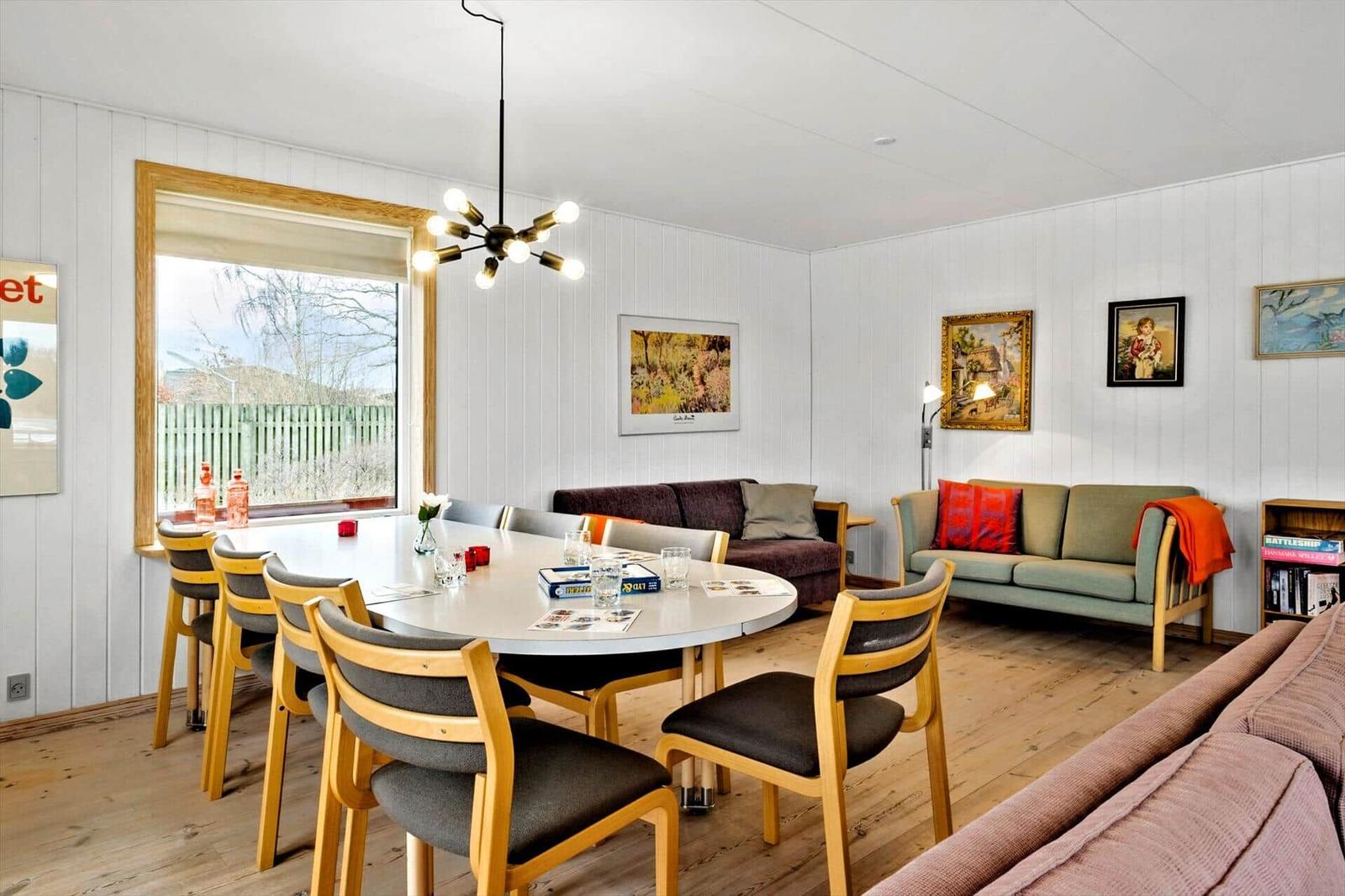 Dining room with round table, chairs, and sofa. Walls with pictures and window.