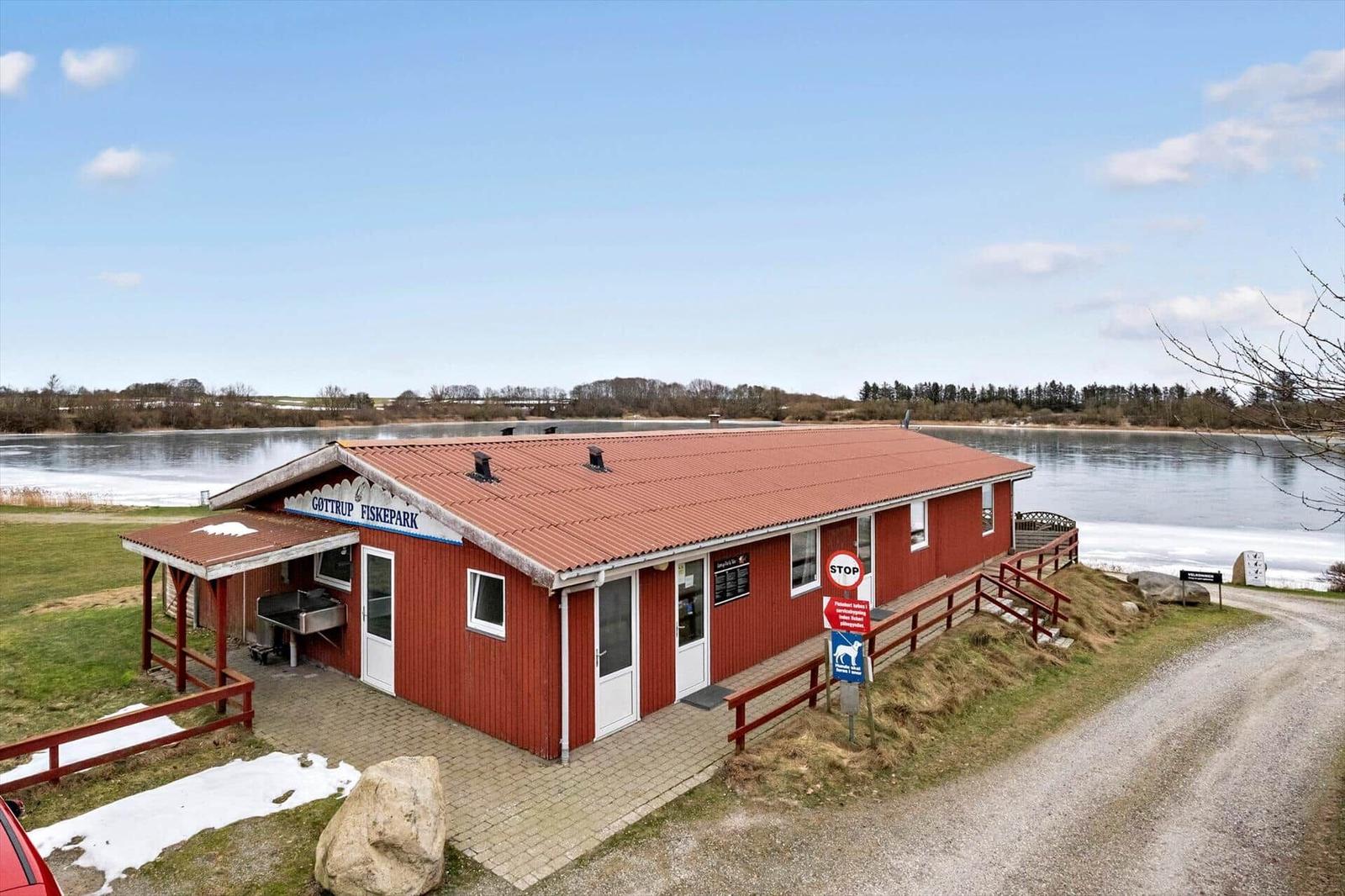 Red building by the lake with grill and entrance area.