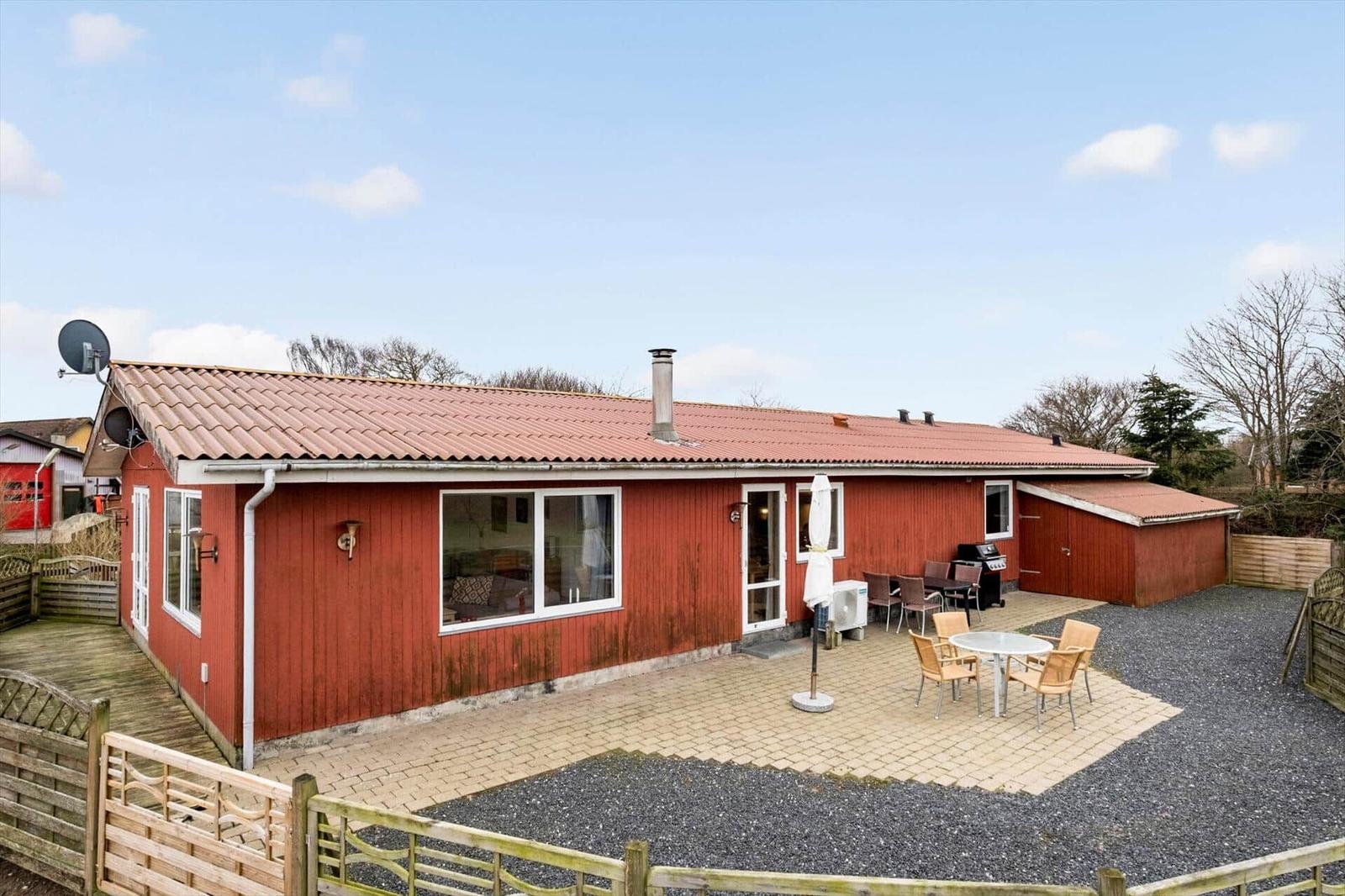 Red house with patio, grill, and outdoor seating area.