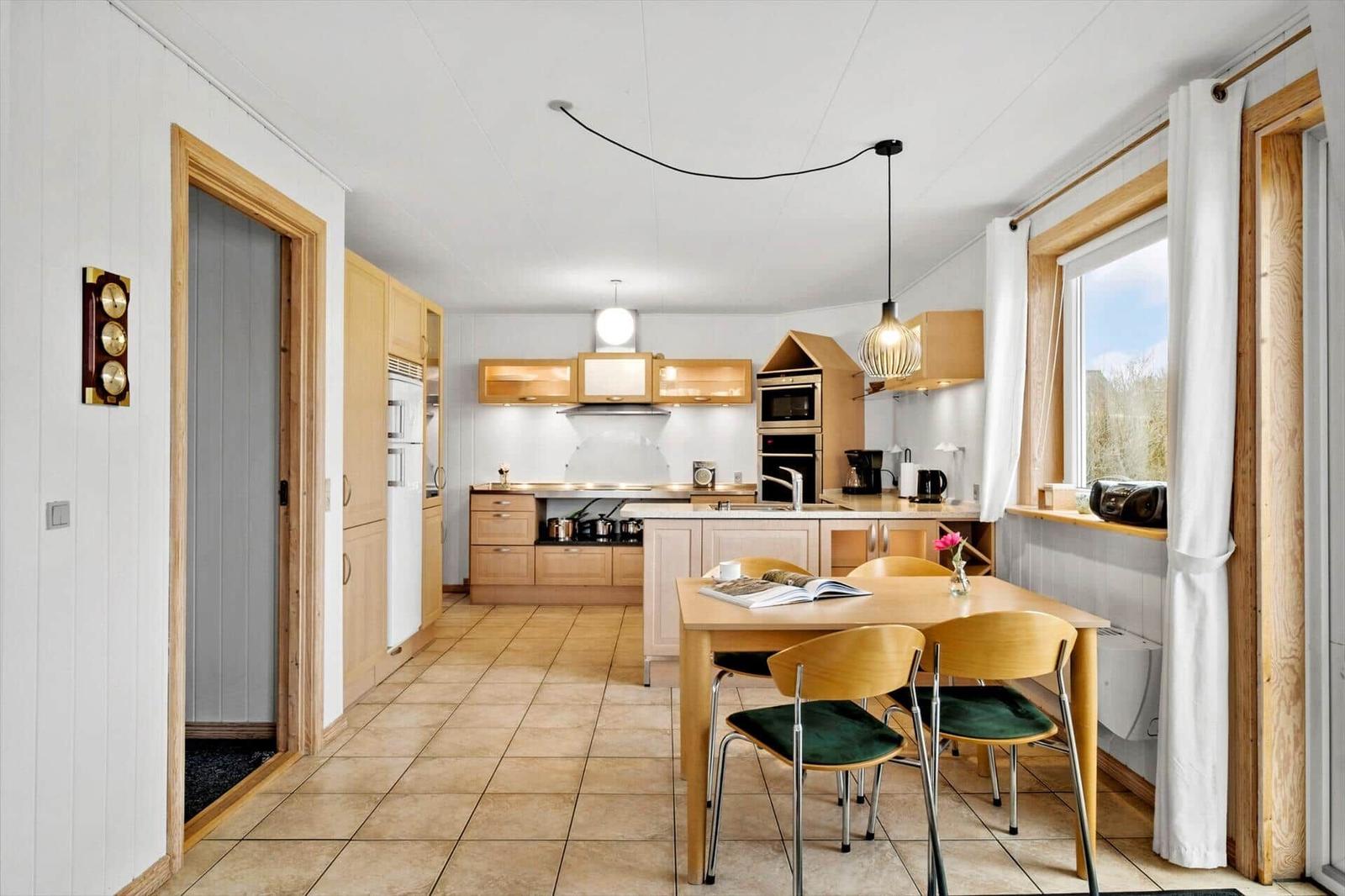 Kitchen with dining area, wooden furniture, and window. Appliances and decor visible.