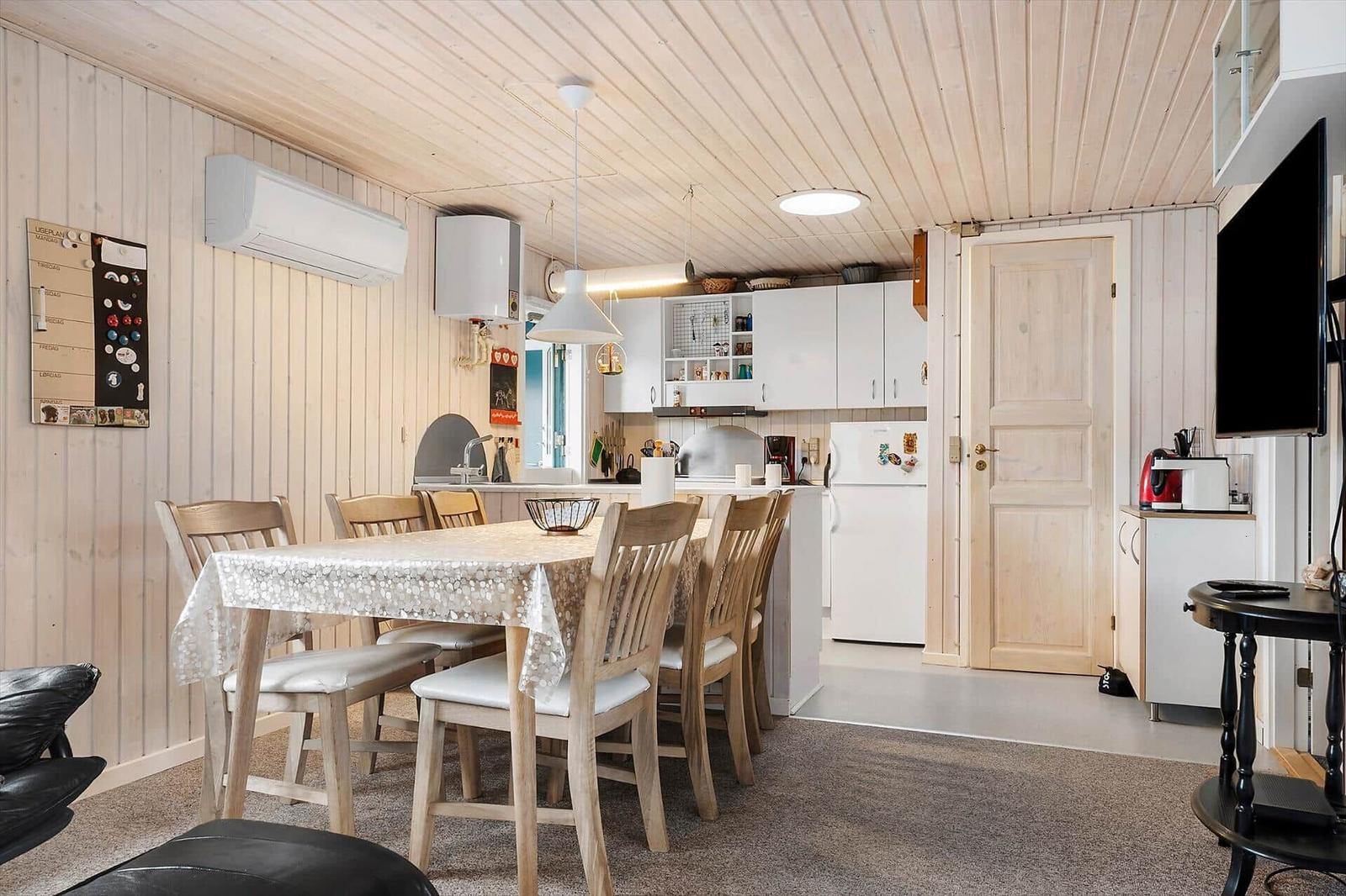 Küche und Essbereich mit Holzwänden und -decke. Tisch mit Stühlen und Küchenschränke.
